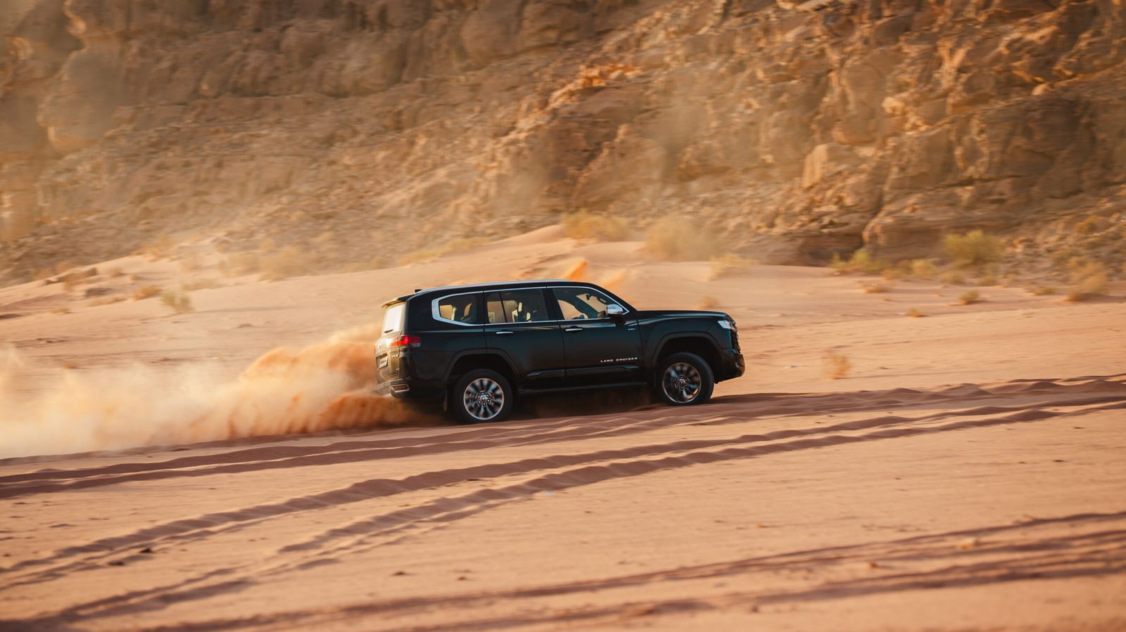 Toyota Land Cruiser 300 HEV throwing sand across the Wadi Rum desert floor